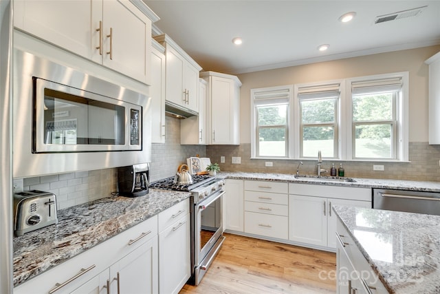 4511 Middlebury Ln, Fort Mill, SC 29715 - kitchen featuring stainless steel appliances, a sink, backsplash, white cabinets, and light wood finished floors