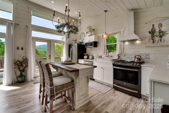 354 Ivy Ridge Cir, Sylva, NC 29779 - kitchen featuring appliances with stainless steel finishes, wall chimney exhaust hood, wooden ceiling, wooden walls, and light wood-style flooring