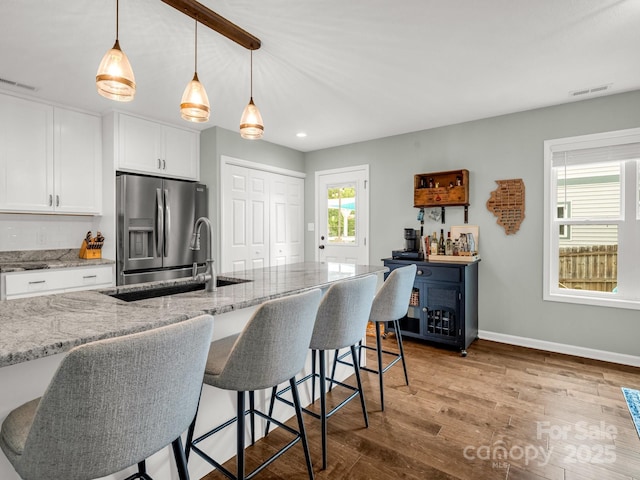 725 Center St, Asheville, NC 28803 - kitchen with stainless steel refrigerator with ice dispenser, a sink, wood finished floors, white cabinets, and baseboards