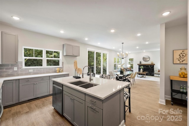 126 Meadow Glen Dr, Troutman, NC 28166 - kitchen featuring gray cabinetry, a sink, stainless steel dishwasher, a chandelier, and light wood-style floors