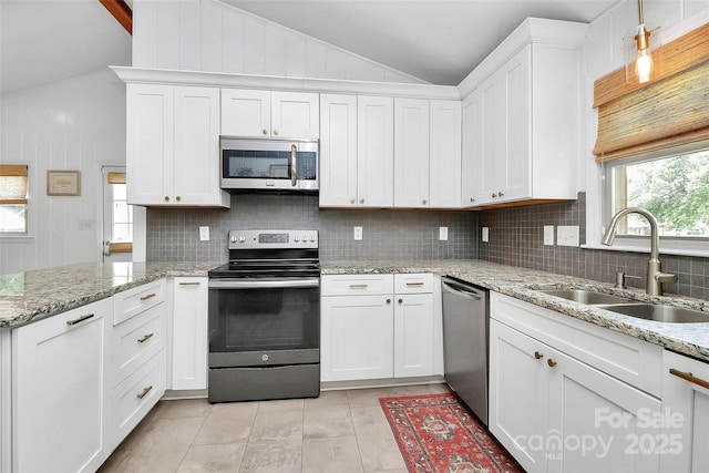 5929 Brookhaven Rd, Charlotte, NC 28210 - kitchen with stainless steel appliances, vaulted ceiling, a sink, backsplash, and white cabinetry