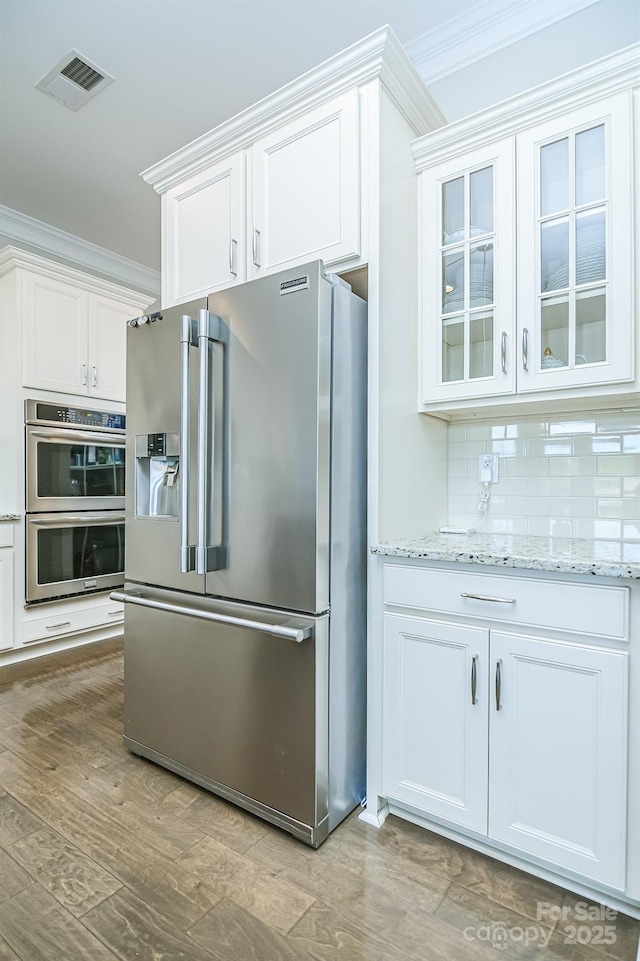 424 Cassia Ct, Fort Mill, SC 29708 - kitchen featuring stainless steel appliances, ornamental molding, white cabinetry, glass insert cabinets, and light wood-type flooring