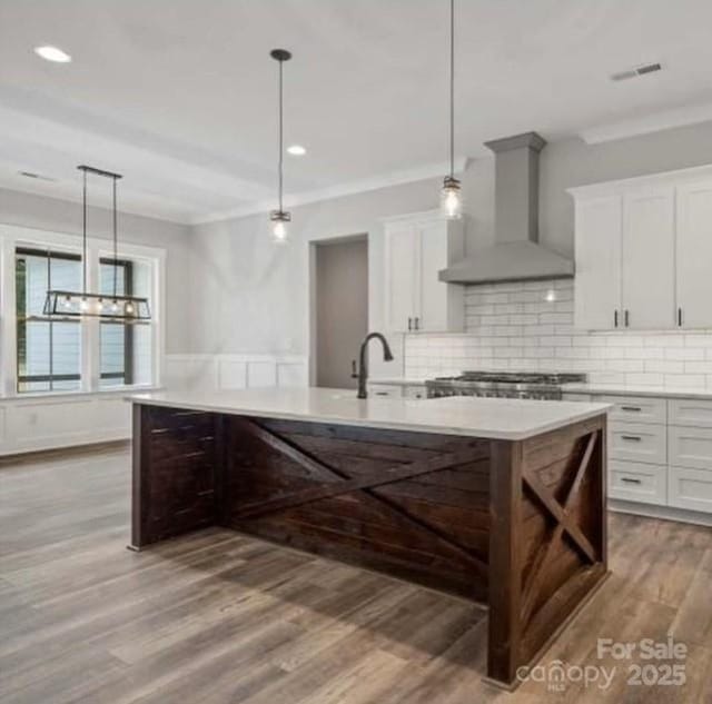 867 Bellegray Rd, Clover, SC 29710 - kitchen with wall chimney exhaust hood, light wood-style floors, light countertops, white cabinets, and decorative backsplash