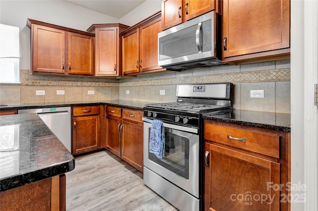 1017 Quail Run Ct, Indian Land, SC 29707 - kitchen featuring stainless steel appliances, dark stone counters, light wood-style flooring, and brown cabinets