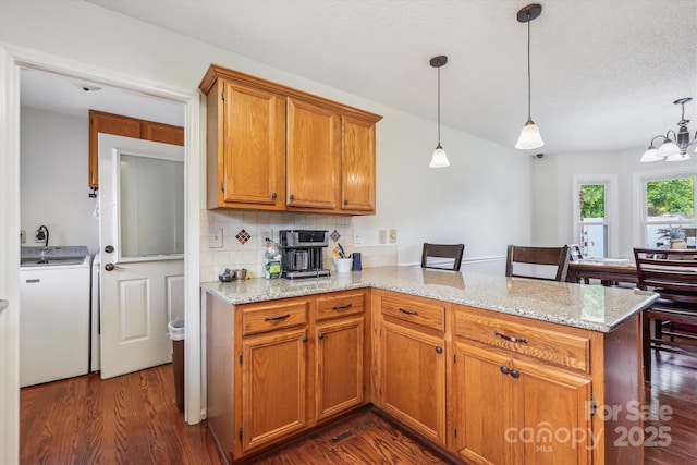 4527 Marshall Ct, Monroe, NC 28110 - kitchen featuring washer / dryer, a peninsula, dark wood-type flooring, tasteful backsplash, and brown cabinets