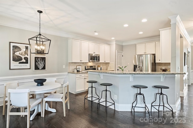 2844 Georgia Ave, Charlotte, NC 28205 - kitchen with stainless steel appliances, a breakfast bar area, dark wood finished floors, a peninsula, and crown molding