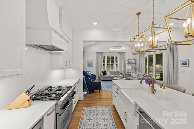 6013 Camile Ct, Charlotte, NC 28226 - kitchen with custom range hood, a chandelier, open floor plan, wood finished floors, and white cabinetry