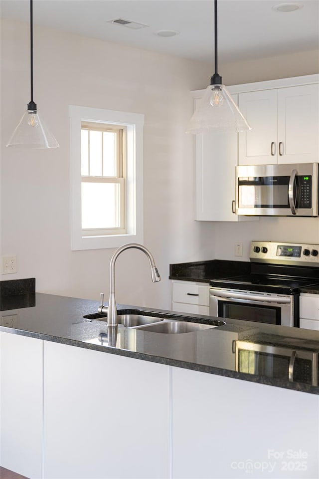 82 Wheeler Rd, Weaverville, NC 28787 - kitchen featuring stainless steel appliances, a sink, dark countertops, white cabinets, and hanging light fixtures
