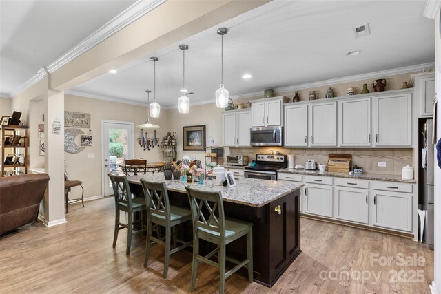 6010 Hawk View Rd, Waxhaw, NC 28173 - kitchen with stainless steel appliances, a kitchen bar, tasteful backsplash, light stone countertops, and a kitchen island with sink