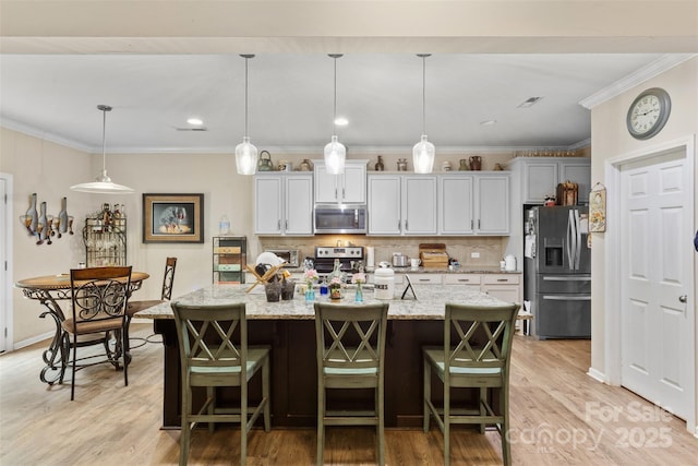 6010 Hawk View Rd, Waxhaw, NC 28173 - kitchen featuring appliances with stainless steel finishes, light wood-style flooring, backsplash, an island with sink, and a kitchen breakfast bar