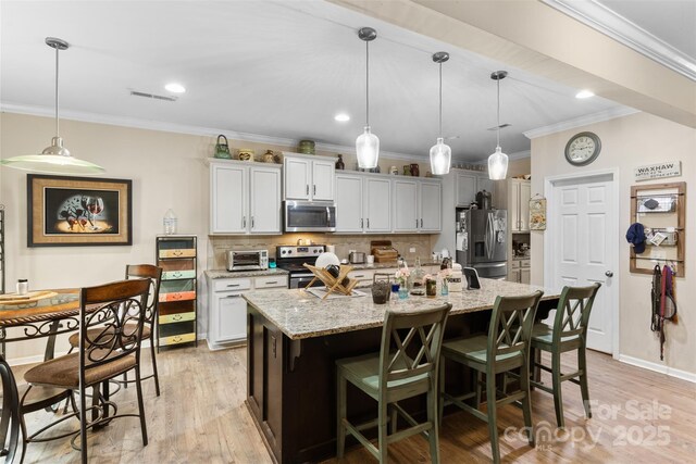 6010 Hawk View Rd, Waxhaw, NC 28173 - kitchen with stainless steel appliances, ornamental molding, backsplash, an island with sink, and a breakfast bar