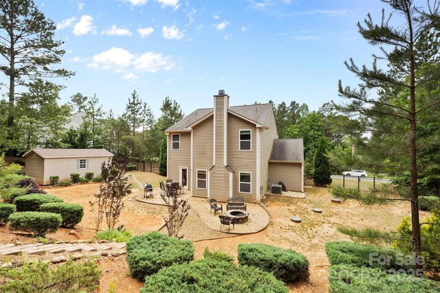 6010 Hawk View Rd, Waxhaw, NC 28173 - back of house with a fire pit, a chimney, a patio, an outdoor structure, and view of scattered trees