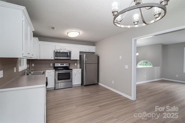 1520 28th St SW, Hickory, NC 28602 - kitchen featuring stainless steel appliances, a chandelier, a sink, light wood-style flooring, and a textured ceiling