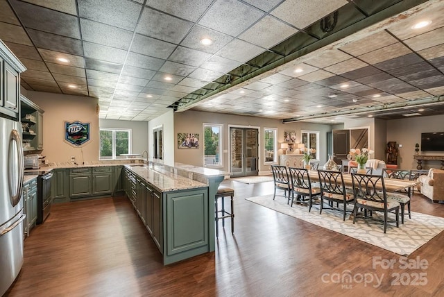 109 Oak Forest Dr, Kings Mountain, NC 28086 - kitchen featuring a peninsula, dark wood-type flooring, appliances with stainless steel finishes, green cabinetry, and a kitchen breakfast bar