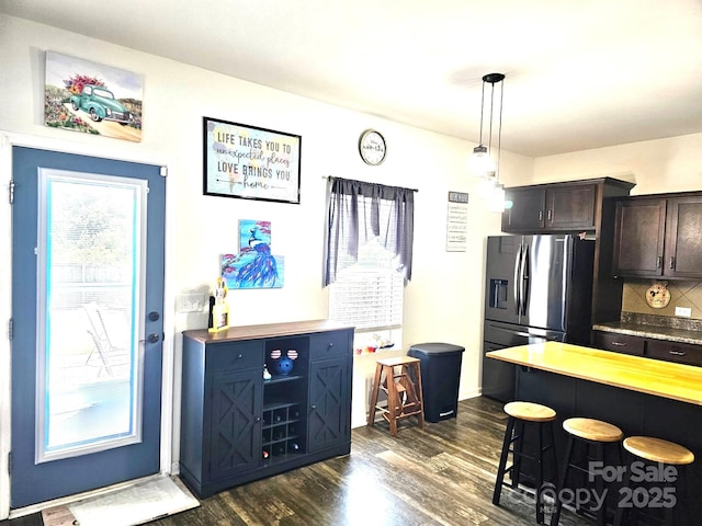189 Fesperman Cir, Troutman, NC 28166 - kitchen with a breakfast bar, stainless steel fridge with ice dispenser, dark wood-style flooring, dark brown cabinetry, and tasteful backsplash