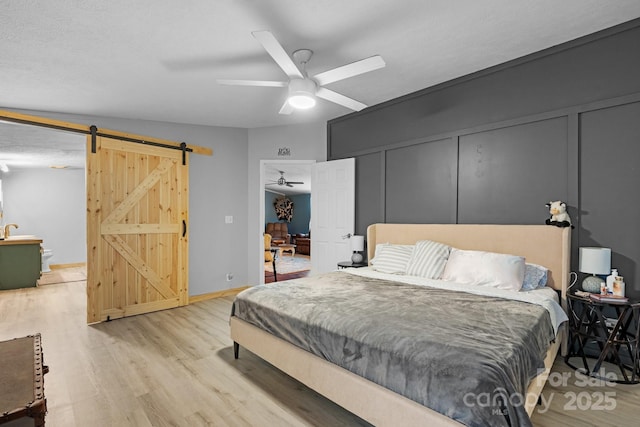 5366 Hayes Waters Rd, Morganton, NC 28655 - bedroom featuring a barn door, wood finished floors, ceiling fan, and baseboards