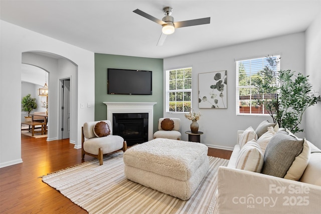 10027 Juniper Trace Dr, Charlotte, NC 28277 - living area with ceiling fan, arched walkways, wood finished floors, a glass covered fireplace, and baseboards