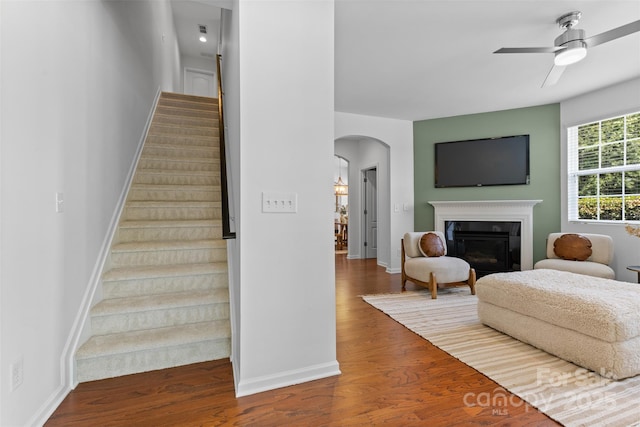 10027 Juniper Trace Dr, Charlotte, NC 28277 - stairway featuring arched walkways, a ceiling fan, a glass covered fireplace, wood finished floors, and baseboards