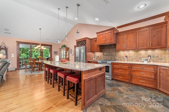 560 Blue Sky Dr, Dallas, NC 28034 - kitchen featuring stainless steel appliances, a chandelier, brown cabinetry, a kitchen breakfast bar, and backsplash