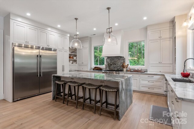 3020 Brooks Mill Ln, Wingate, NC 28174 - kitchen with built in refrigerator, a sink, light wood-type flooring, light stone counters, and white cabinetry