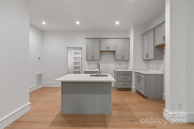 3020 Brooks Mill Ln, Wingate, NC 28174 - kitchen featuring gray cabinets, a sink, a center island with sink, light wood-style flooring, and recessed lighting