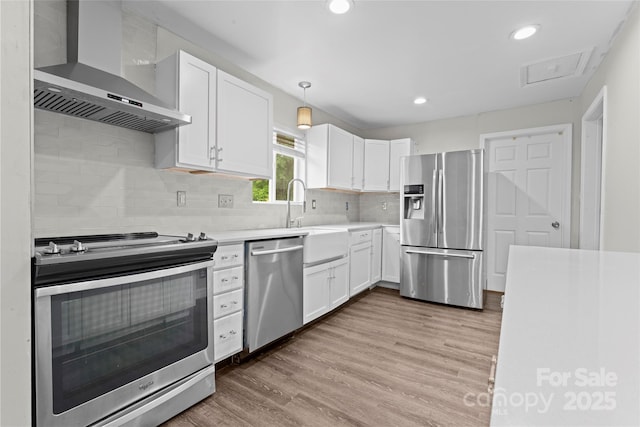 3400 Reid Ave, Charlotte, NC 28208 - kitchen with stainless steel appliances, wall chimney range hood, white cabinetry, light countertops, and recessed lighting