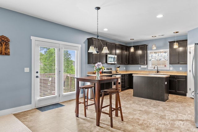 21 Henbit Way, Arden, NC 28704 - kitchen with stainless steel appliances, dark brown cabinets, light countertops, a center island, and decorative light fixtures