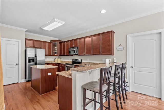 1070 Blueberry Rd, Salisbury, NC 28147 - kitchen featuring appliances with stainless steel finishes, a kitchen island, ornamental molding, light stone countertops, and a peninsula
