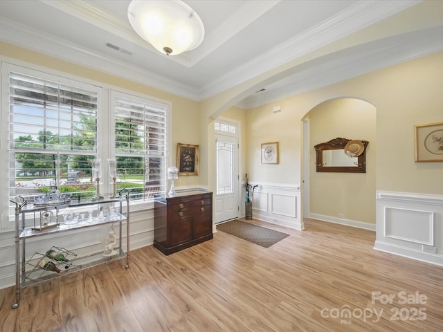 1004 Fairbanks Ct, Indian Trail, NC 28079 - foyer featuring arched walkways, a decorative wall, ornamental molding, light wood-type flooring, and wainscoting