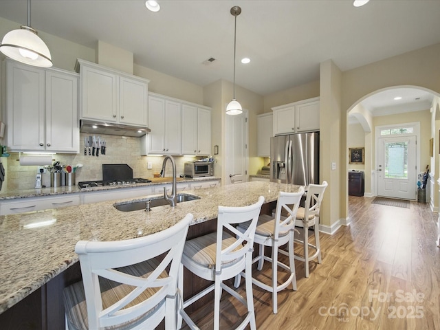 1004 Fairbanks Ct, Indian Trail, NC 28079 - kitchen featuring appliances with stainless steel finishes, a sink, arched walkways, white cabinetry, and light wood finished floors