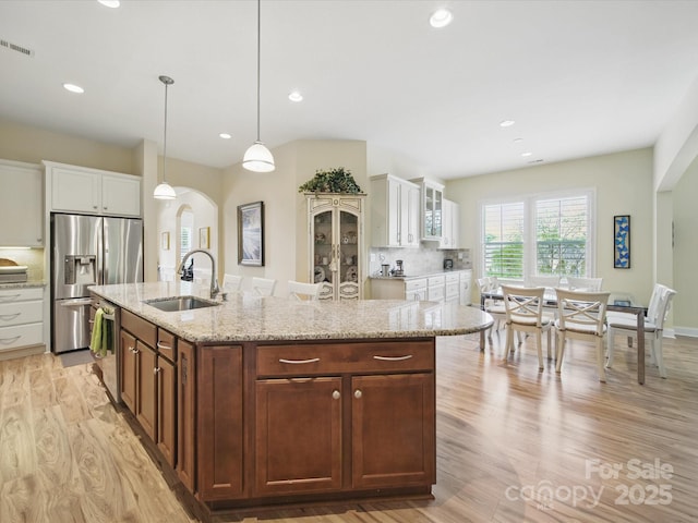 1004 Fairbanks Ct, Indian Trail, NC 28079 - kitchen featuring arched walkways, a sink, appliances with stainless steel finishes, light wood finished floors, and white cabinets