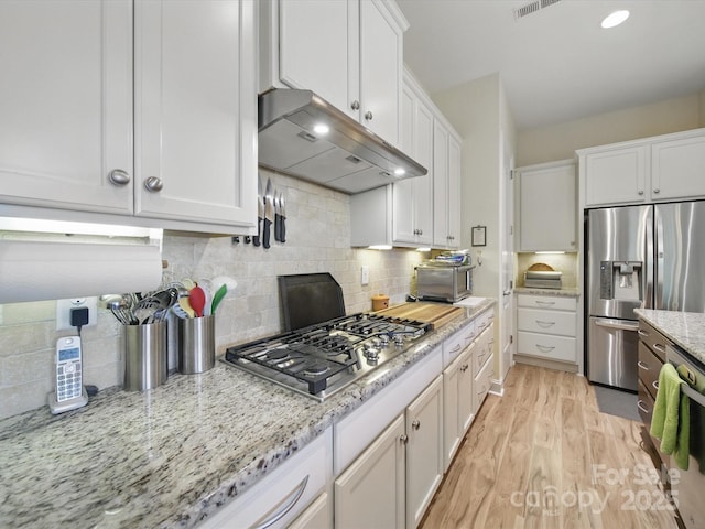 1004 Fairbanks Ct, Indian Trail, NC 28079 - kitchen featuring stainless steel appliances, under cabinet range hood, white cabinetry, light wood-type flooring, and decorative backsplash