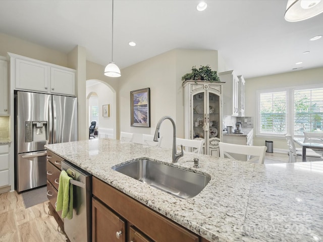 1004 Fairbanks Ct, Indian Trail, NC 28079 - kitchen featuring stainless steel appliances, a sink, arched walkways, light stone counters, and hanging light fixtures
