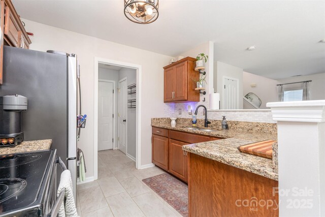2636 Forest Grove Ct, Charlotte, NC 28269 - kitchen with a sink, brown cabinets, tasteful backsplash, range with electric cooktop, and light stone countertops