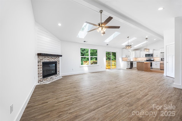 2027 Marquesas Ave, Tega Cay, SC 29708 - unfurnished living room with a skylight, beam ceiling, wood finished floors, a fireplace, and high vaulted ceiling