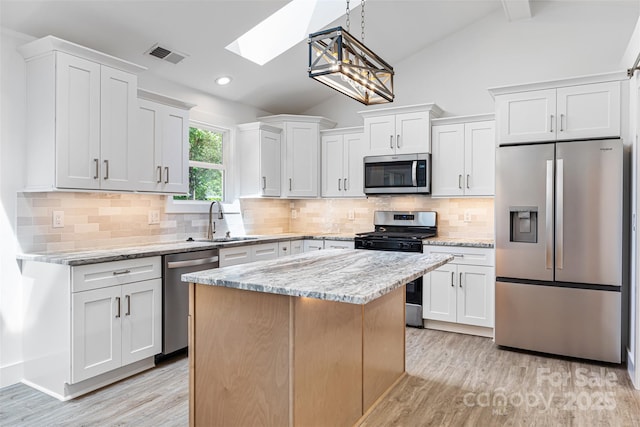 2027 Marquesas Ave, Tega Cay, SC 29708 - kitchen featuring stainless steel appliances, a skylight, lofted ceiling, light wood-type flooring, and white cabinetry