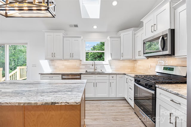 2027 Marquesas Ave, Tega Cay, SC 29708 - kitchen with stainless steel appliances, recessed lighting, a skylight, white cabinetry, and light stone counters