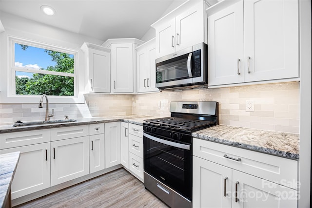 2027 Marquesas Ave, Tega Cay, SC 29708 - kitchen featuring stainless steel appliances, white cabinetry, light stone counters, decorative backsplash, and light wood finished floors