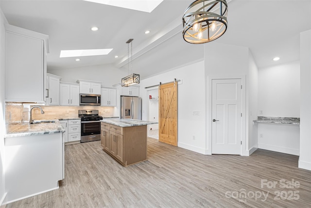 2027 Marquesas Ave, Tega Cay, SC 29708 - kitchen with appliances with stainless steel finishes, a skylight, vaulted ceiling, light wood-style floors, and decorative backsplash