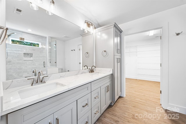 2027 Marquesas Ave, Tega Cay, SC 29708 - bathroom featuring double vanity, a stall shower, wood finished floors, and a walk in closet