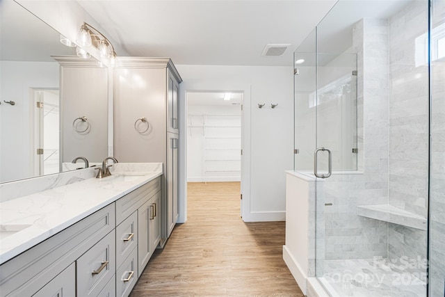 2027 Marquesas Ave, Tega Cay, SC 29708 - bathroom featuring double vanity, a shower stall, wood finished floors, and a walk in closet