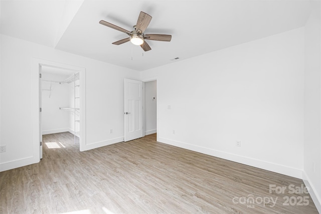 2027 Marquesas Ave, Tega Cay, SC 29708 - unfurnished bedroom with light wood finished floors, a walk in closet, a ceiling fan, and a closet