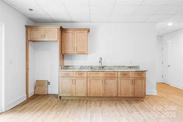 2027 Marquesas Ave, Tega Cay, SC 29708 - kitchen with light wood-style flooring, light stone counters, a drop ceiling, and brown cabinets