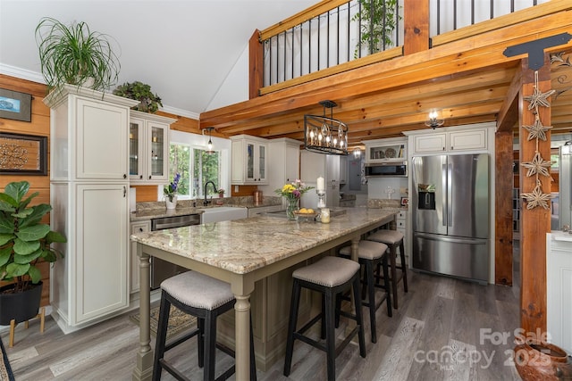 334 Arbra Mountain Way, Bostic, NC 28018 - kitchen featuring appliances with stainless steel finishes, a kitchen island, wood finished floors, light stone countertops, and high vaulted ceiling