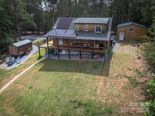 334 Arbra Mountain Way, Bostic, NC 28018 - back of house with an outdoor structure, roof mounted solar panels, a lawn, a wooded view, and a deck