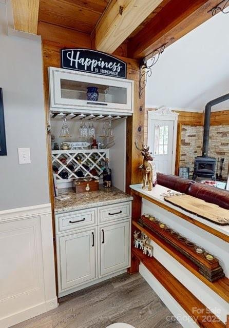 334 Arbra Mountain Way, Bostic, NC 28018 - indoor dry bar with a wood stove, beamed ceiling, light wood finished floors, wainscoting, and a decorative wall