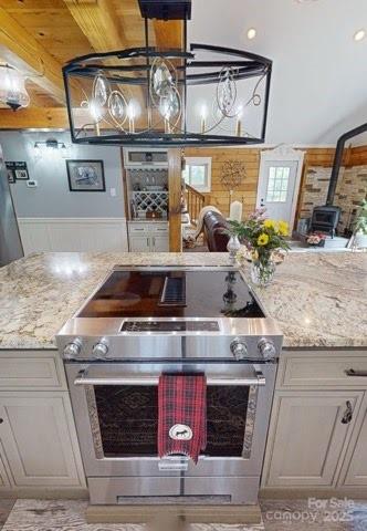 334 Arbra Mountain Way, Bostic, NC 28018 - kitchen with light stone counters, a wainscoted wall, stainless steel electric stove, and a wood stove