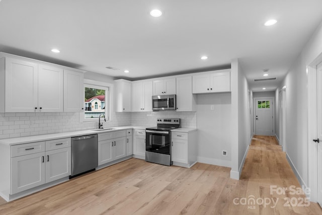 101 Churchill Dr, Kings Mountain, NC 28086 - kitchen featuring appliances with stainless steel finishes, a sink, backsplash, light countertops, and light wood-style floors