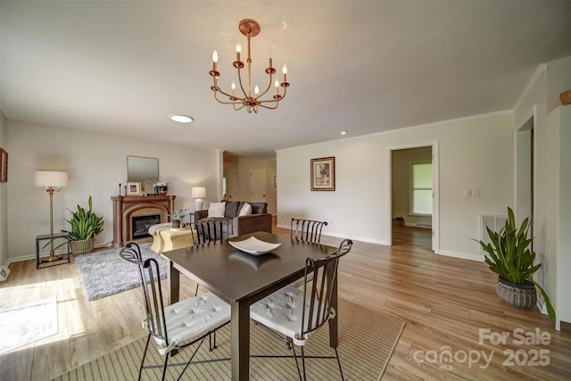 801 Witmore Rd, Wingate, NC 28174 - dining space featuring a chandelier, light wood-style flooring, baseboards, a glass covered fireplace, and ornamental molding
