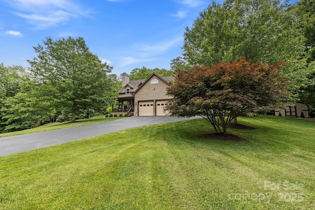 21 School House Rd, Pisgah Forest, NC 28768 - view of property hidden behind natural elements featuring asphalt driveway, a front lawn, an attached garage, and a chimney